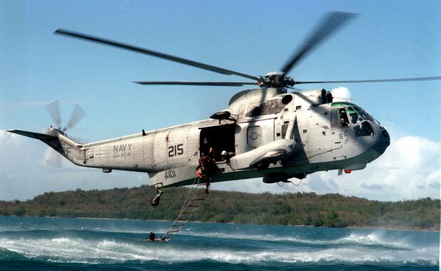 Image: U.S. Navy Sea King helicopter hovers over the water to recover EOD technicians.